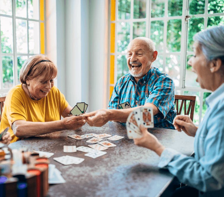 personas mayores felices jugando a las cartas